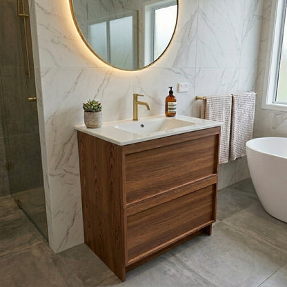 Bathroom with wooden vanity, round mirror, and bathtub.
