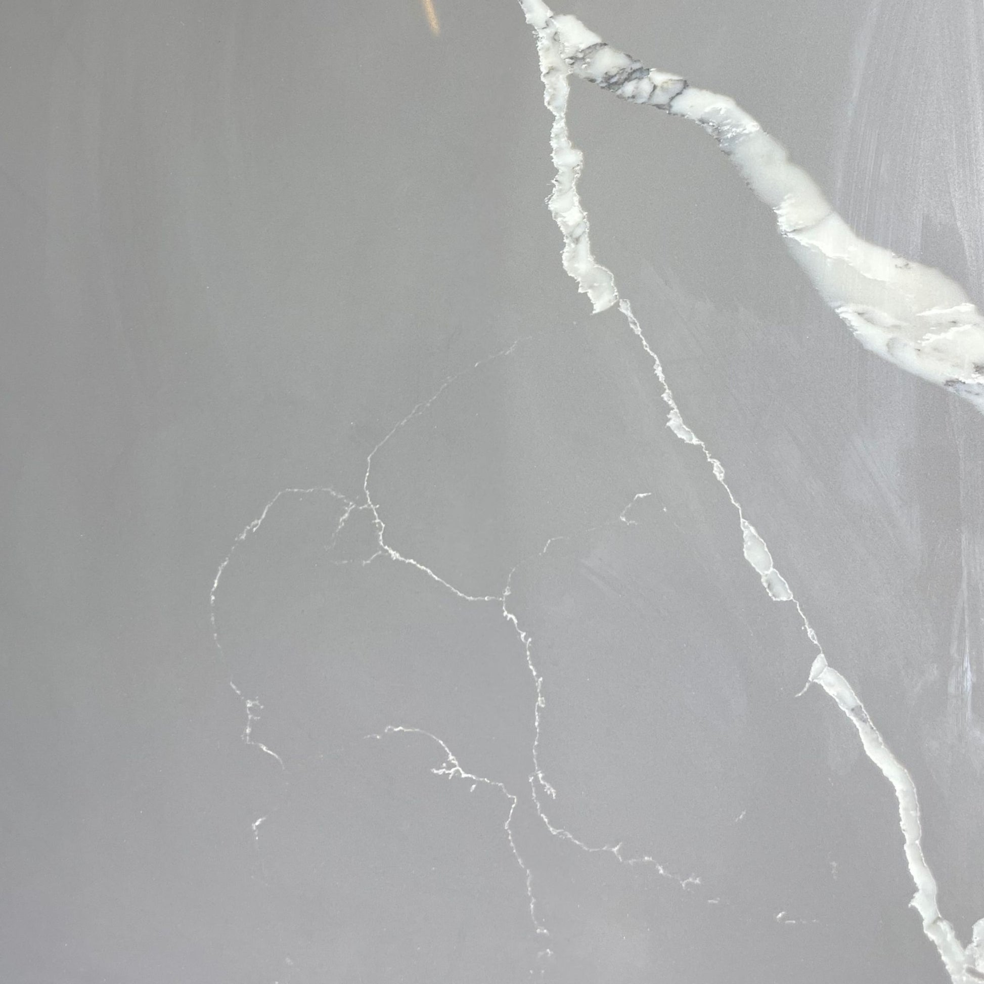 Calacatta grey engineered quartz stone benchtop slab — warm light grey base with bold flowing white marble veining, high gloss polished finish, 30mm custom cut vanity top